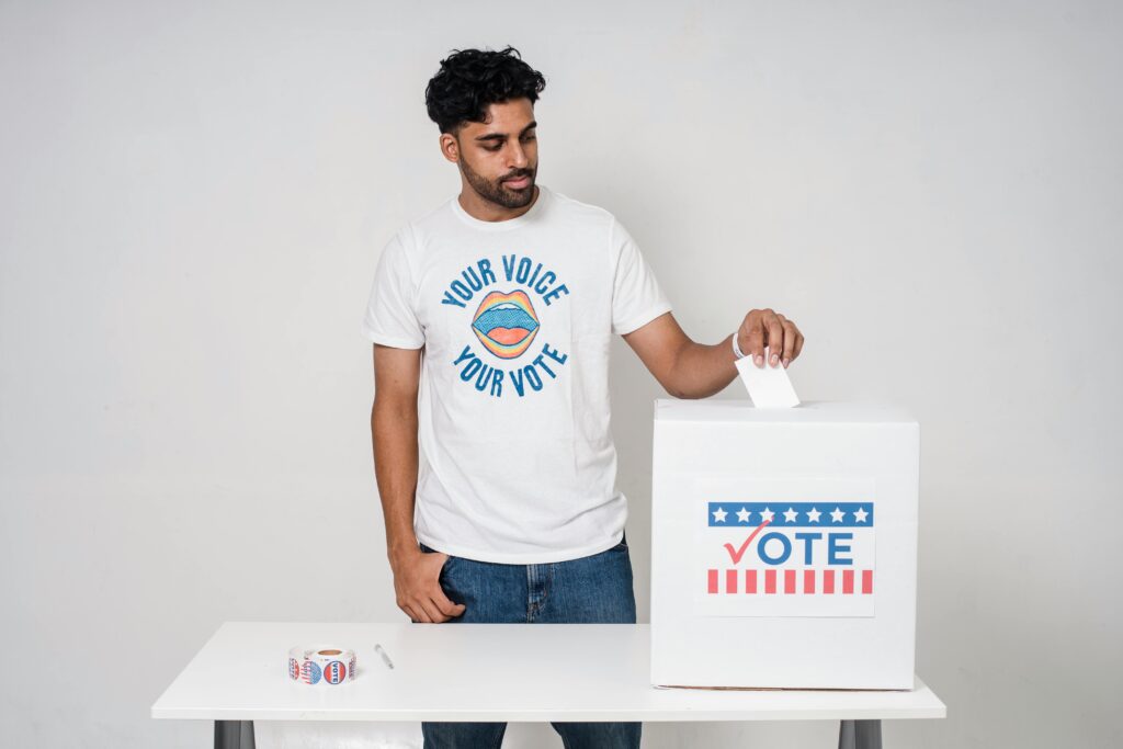 Young man casting a vote into a ballot box on a white background promoting democracy.